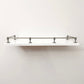 Straight front eye-level view of Black Shadow solid brass gallery railing system mounted on a floating white wall shelf.