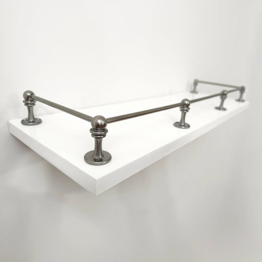 Perspective side view of Black Shadow solid brass gallery rail mounted on a white floating shelf focusing on the front corner post.