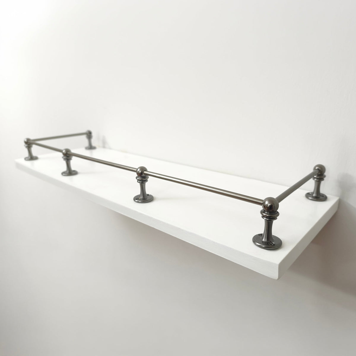Handcrafted Black Shadow brass gallery rail system full assembly with five posts on a floating white shelf, presented in a clean, clear perspective view.