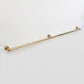 Side angle view of an extra long wall-mounted unlacquered solid brass kitchen rail with center support post on a clean white background.