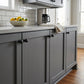 Matte black solid brass ball cabinet knobs installed on dark grey shaker kitchen cabinets with a subway tile backsplash.