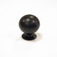 Matte black solid brass spherical ball drawer knob isolated on a white background.