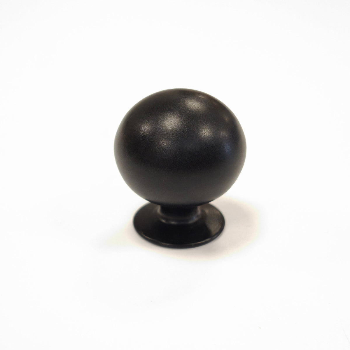 Matte black solid brass spherical ball drawer knob isolated on a white background.