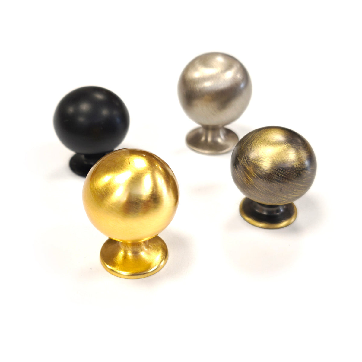 Solid brass spherical ball cabinet knobs shown in four available finishes: polished brass, satin nickel, antique brass, and matte black.