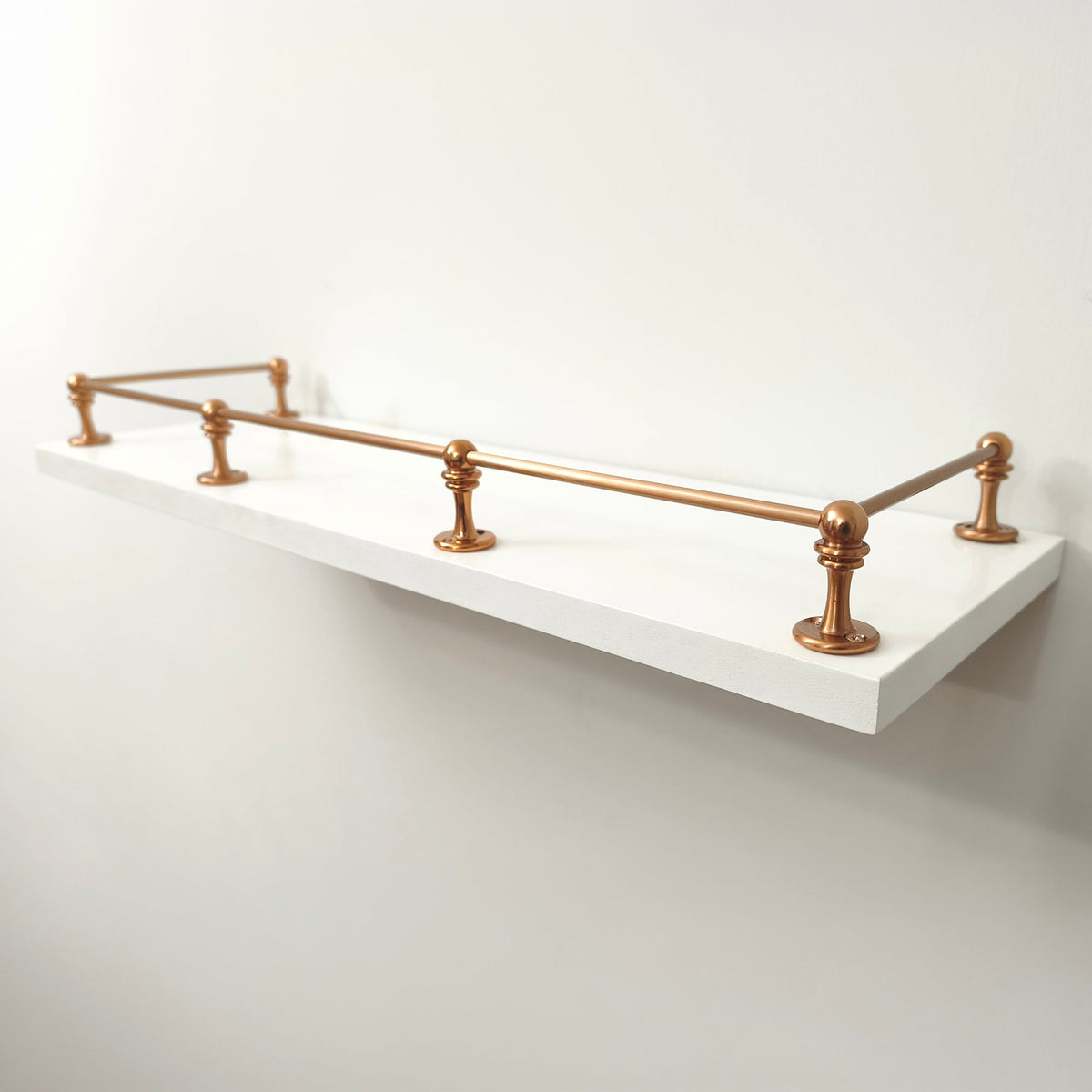 Brass Gallery Rail solid brass shelf gallery rail with warm copper finish mounted on a modern white wall shelf, protecting items with elegant fencing.View 6