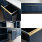 Collage showcasing solid brass drawer topper edge guards installed on navy blue kitchen cabinets with close-up screw detail and pull-out trash drawer.