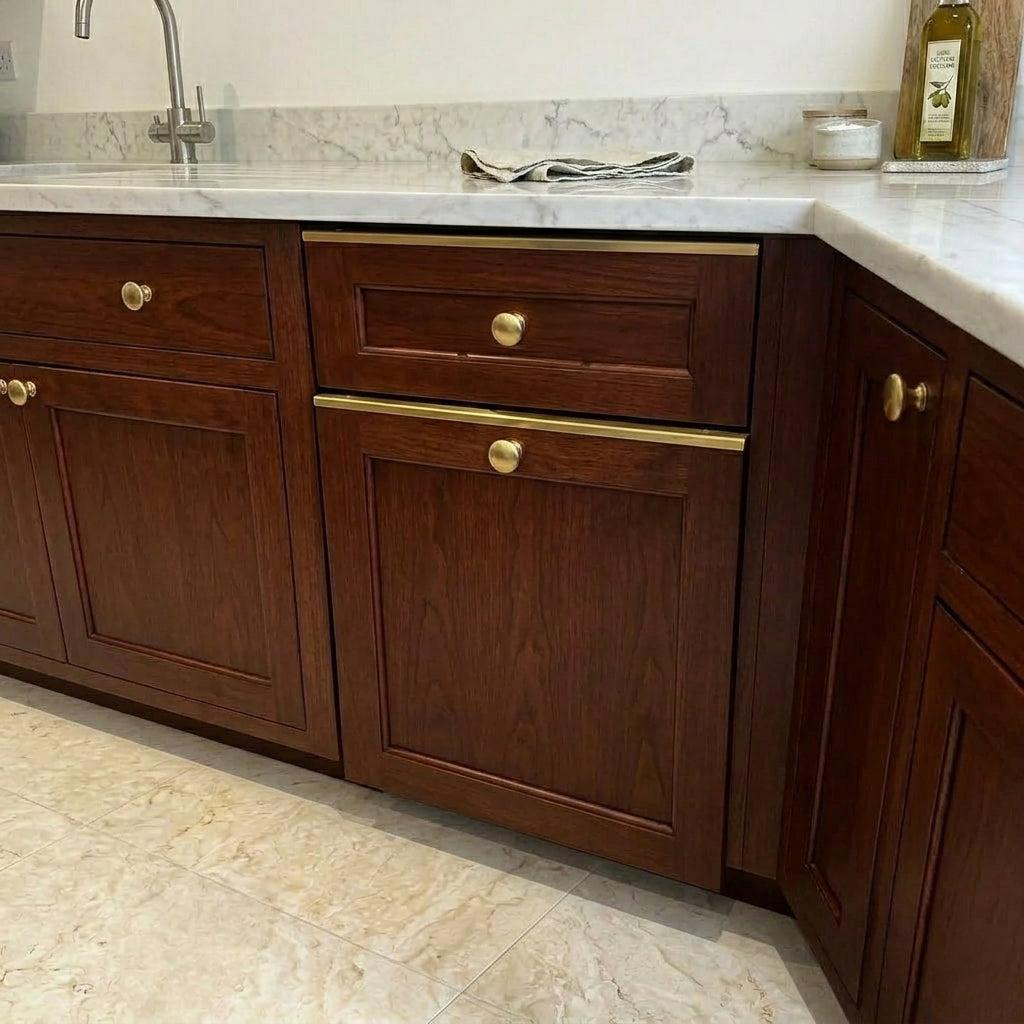 Warm natural wood kitchen cabinets featuring solid brass drawer toppers edge guards paired with brass knobs and marble countertop.