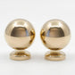 Close-up studio shot of a pair of polished unlacquered solid brass ball drawer knobs on a seamless white background.