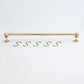 Solid unlacquered brass kitchen hanging rail displayed horizontally with five matching brass S-hooks on a white background.