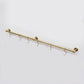 High-angle view of an unlacquered solid brass kitchen hanging rail mounted on a white background with six S-hooks.