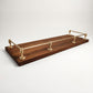 Unlacquered solid brass gallery rail system mounted on a rich dark wood shelf with polished corner and center posts.